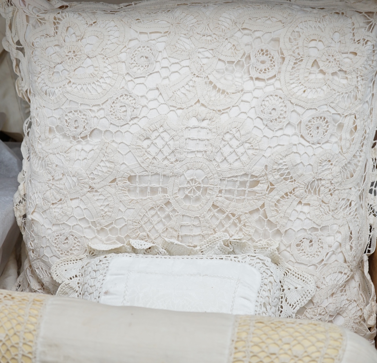 A collection of embroidered and crochet edged table linen, three silk boudoir cushions and a pin cushion. Condition - the linen needs re-laundering and silk cushions have some staining